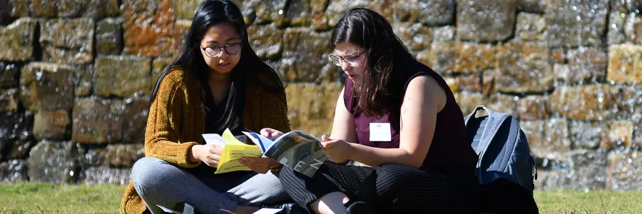 Two students sitting on grass reading